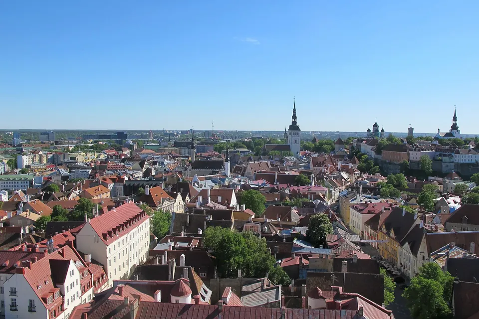 Panoramic view over the red roofs and church spires of Tallinn's old town under a clear sky