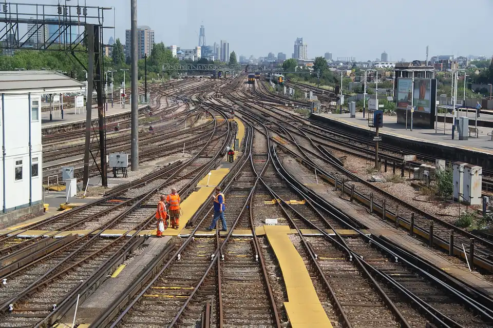 Many railway tracks converging and crossing through sets of points at a large junction, with a city skyline in the distance