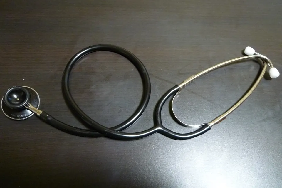 A black stethoscope lying coiled on a dark table