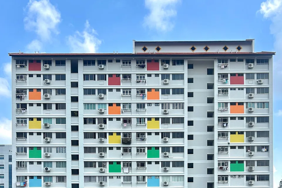 Facade of a tall public housing block in Singapore with rows of windows and coloured panels