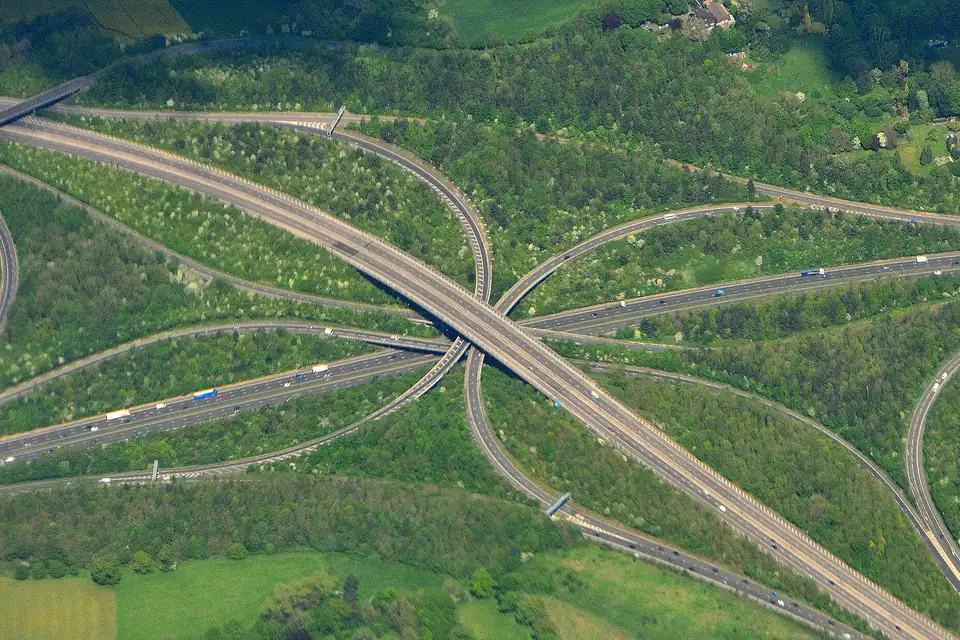 Aerial view of a multi-level motorway interchange with looping slip roads among green fields